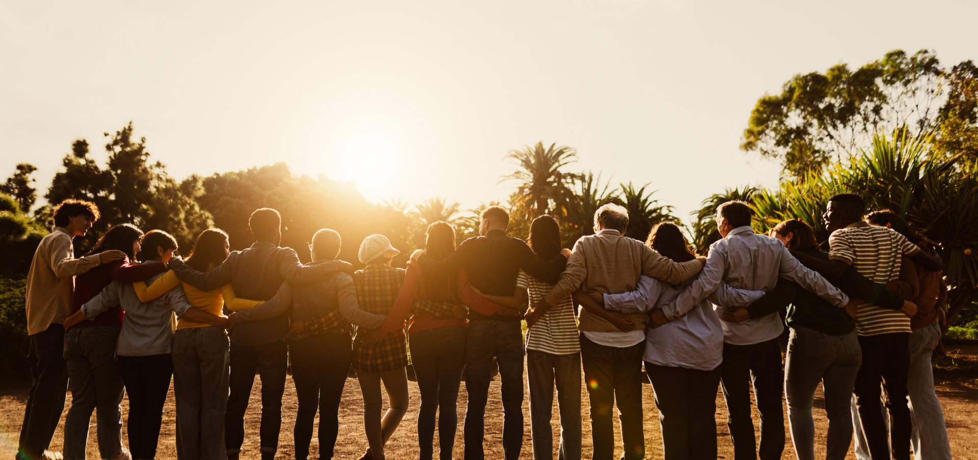 Back view of happy multigenerational people having fun in a public park during sunset time